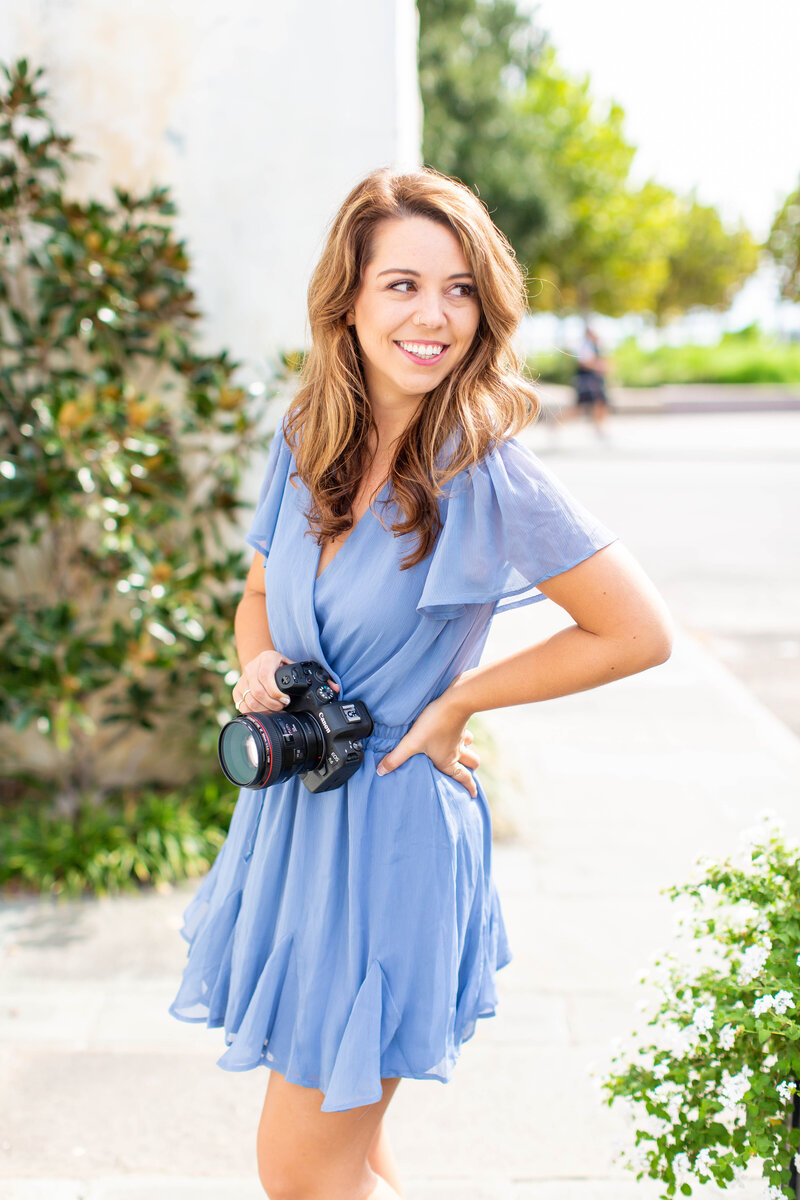 Woman wearing a periwinkle dress and holding a camera