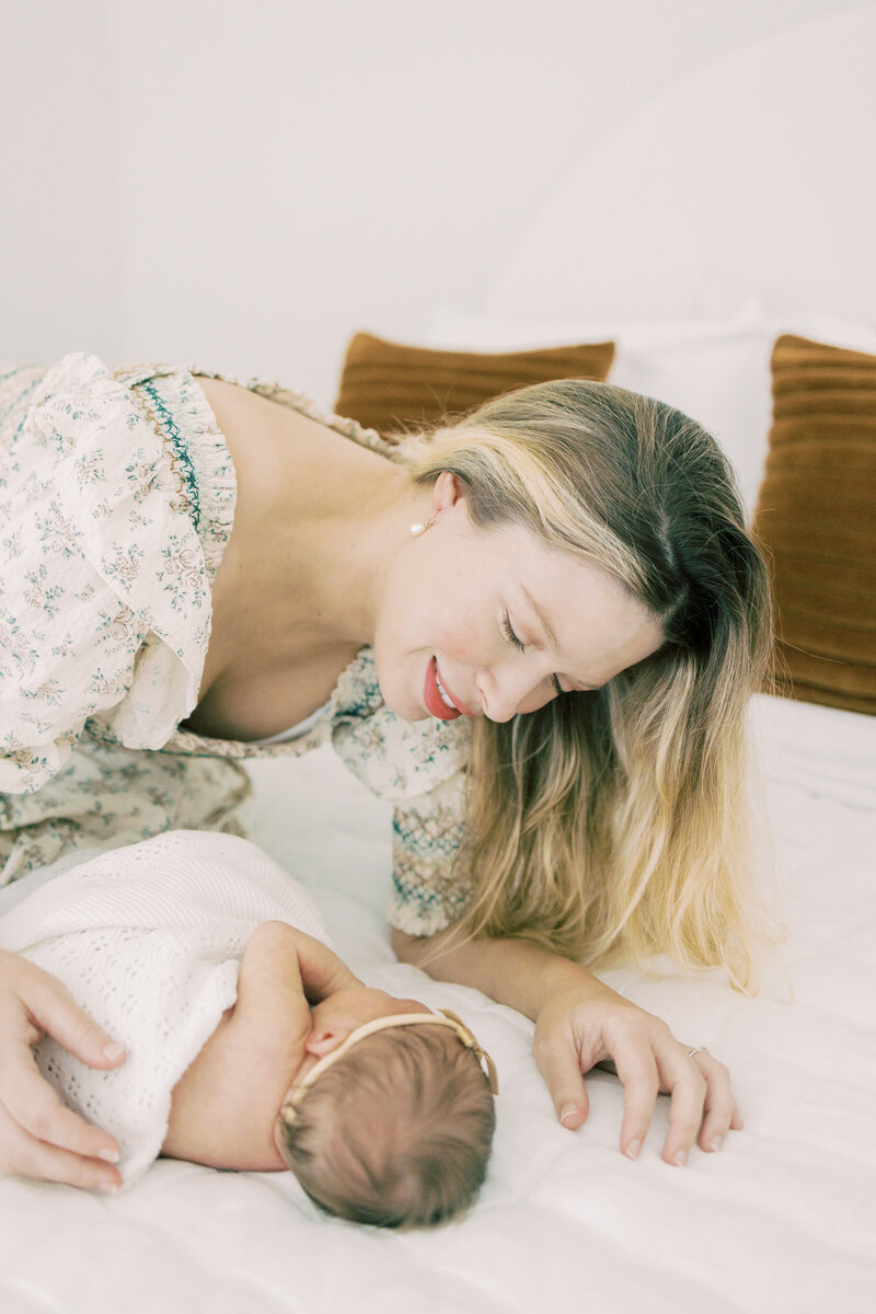Austin mom smiles at her baby on the bed.