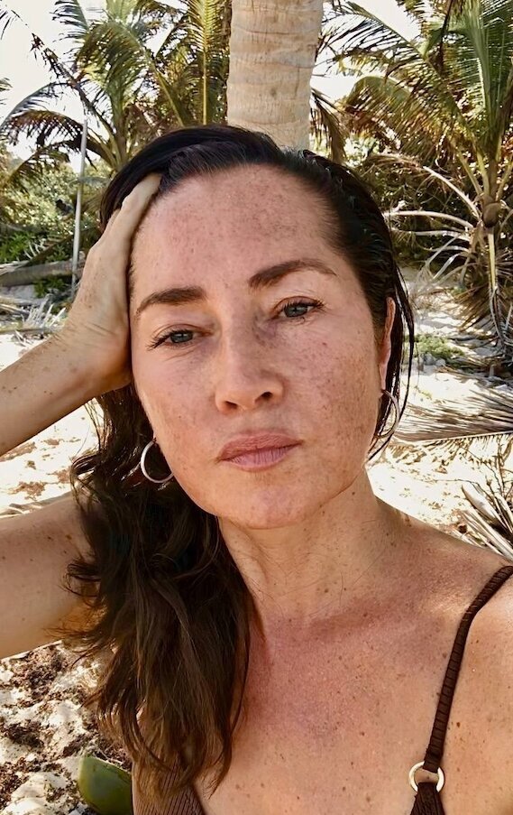 Shannon Echlin, a massage therapist in Tulum, taking a serene beachside moment surrounded by palm trees, embodying intuitive healing and holistic bodywork.