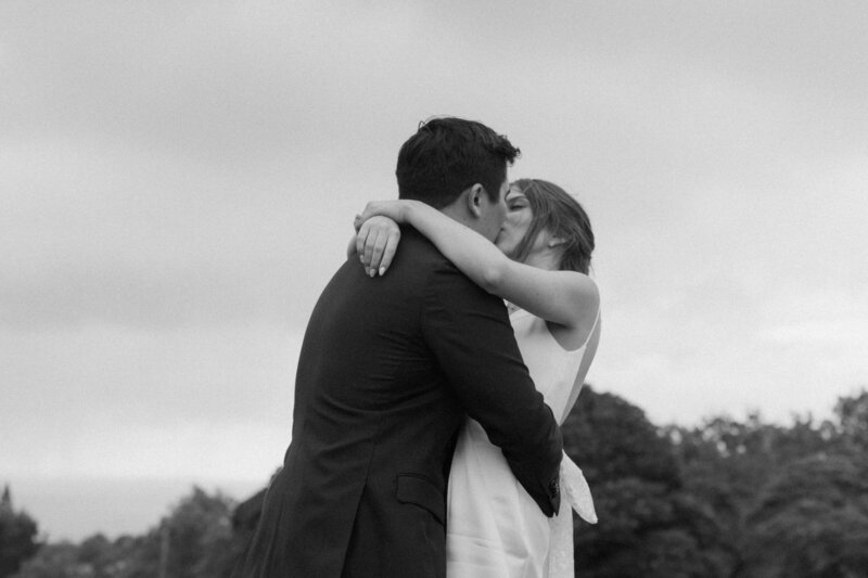 black and white photo of bride and groom kissing