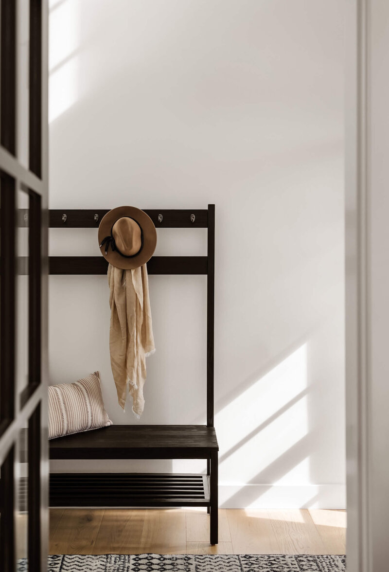 Modern farmhouse entry with black wooden bench with hat and scarf. 