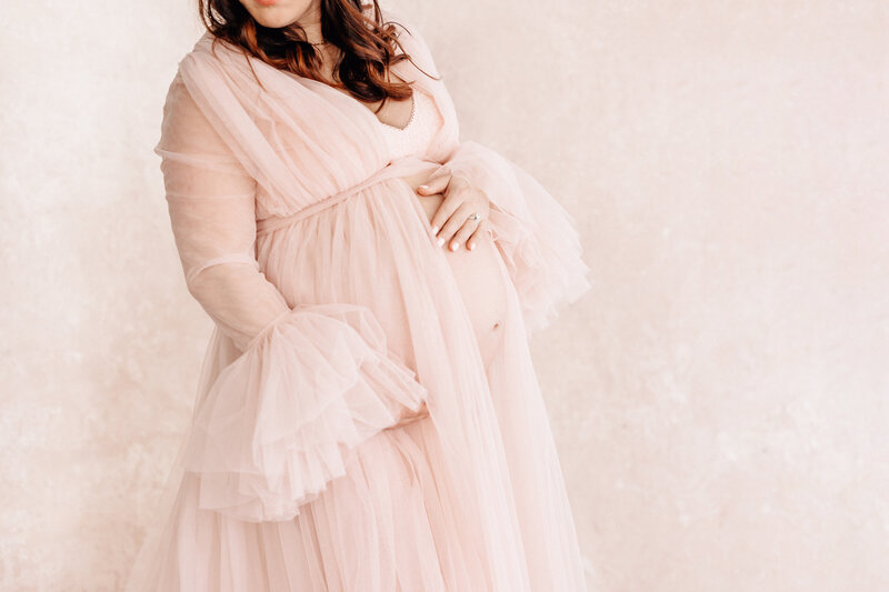 Pregnant Belly Shot of mom against painted pink backdrop