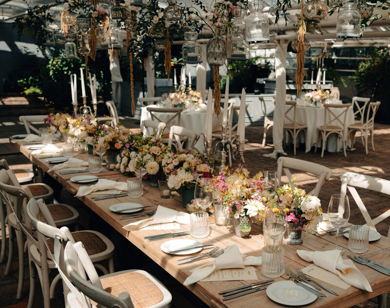 Tables et décor de mariage en extérieur sous un ciel de végétation imaginée dans le cadre d'une organisation de mariage par un wedding planner.