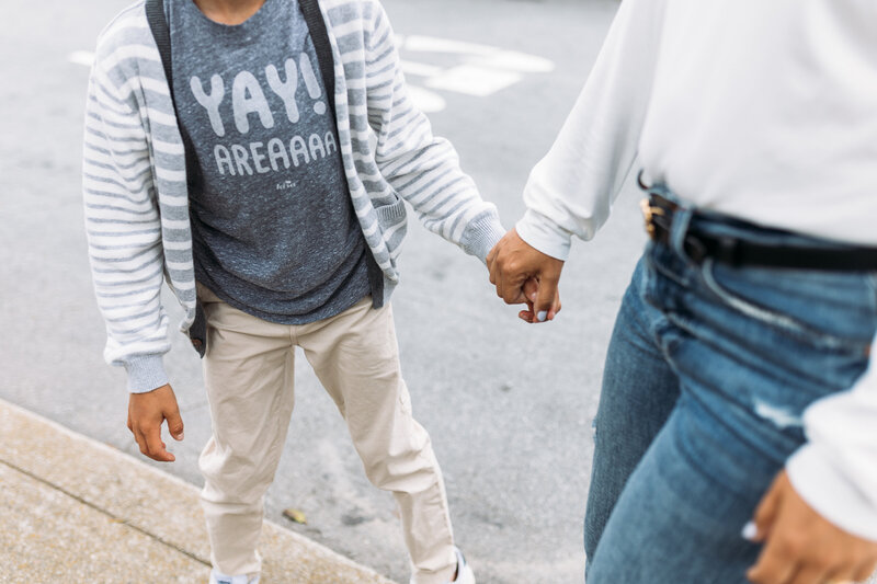 Family Photographer, mom and son hold hands on the sidewalk