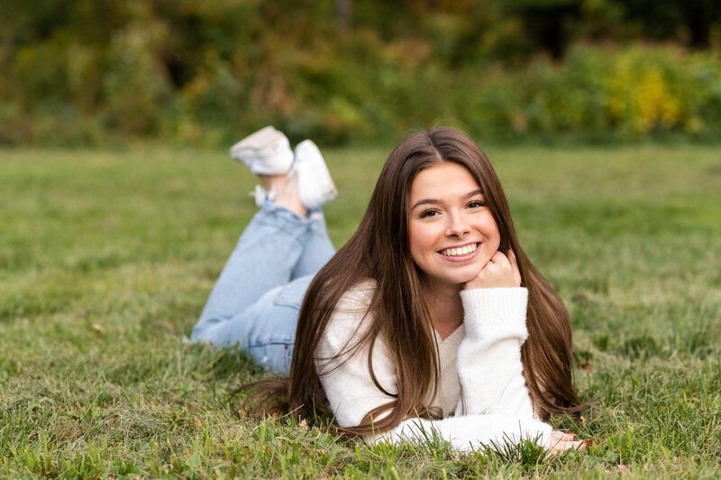 Senior girl laying in grass posing.