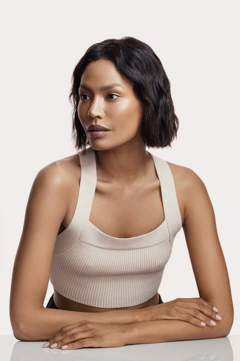 Amira in a relaxed YSL beauty portrait, seated with a calm expression, wearing a neutral-toned outfit, photographed by Ylva Erevall.