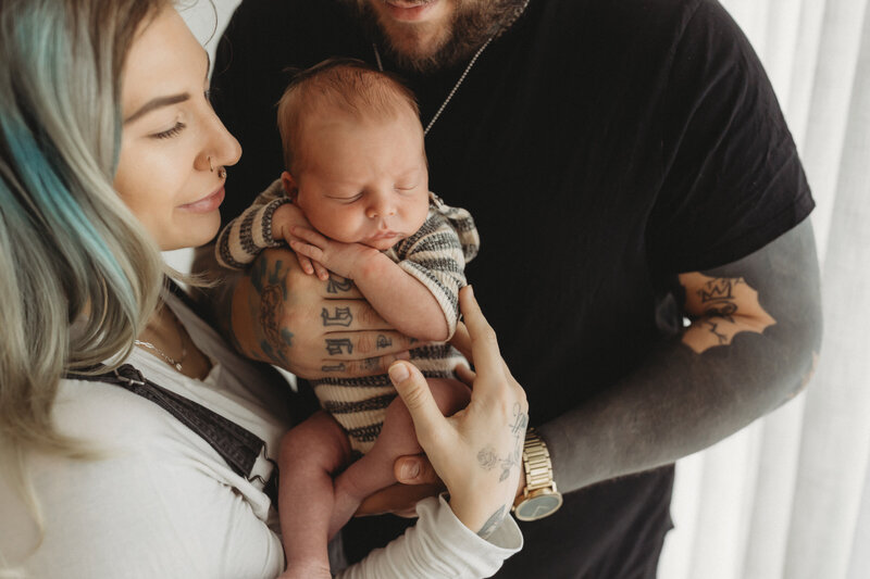 Family photo session of new parents cradling newborn in their hands