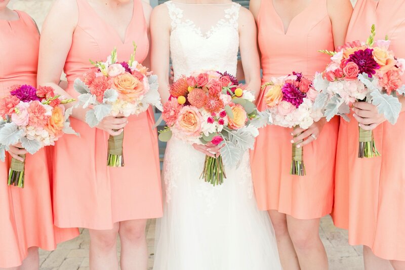 Bridesmaids with coral dresses and bright pink bouquets
