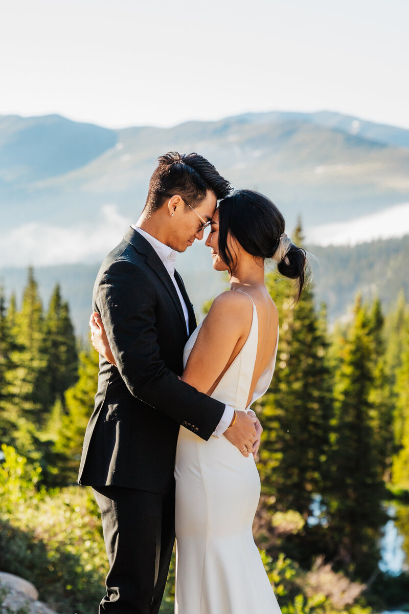 Shannon Lee, a Colorado elopement photographer capturing a tender moment between a couple embracing with a stunning mountain backdrop.