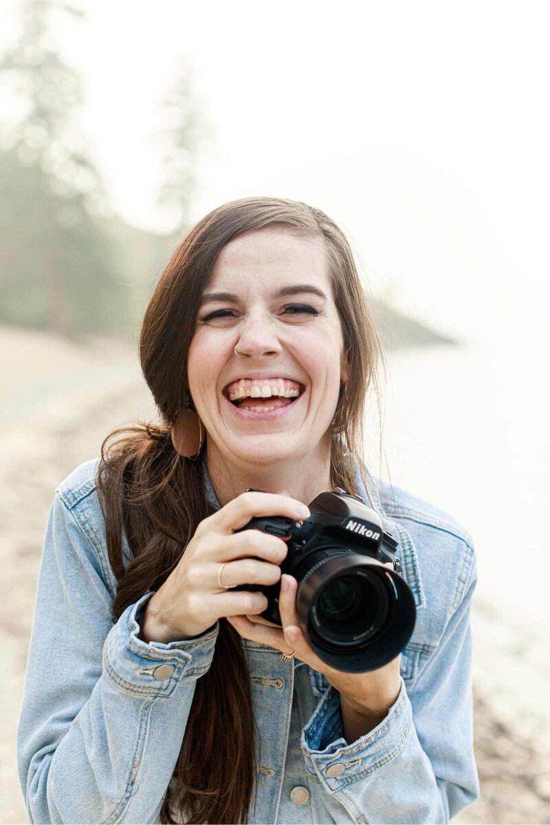 Simply Sandra Yvonne, systems strategist and retired wedding photographer, laughing and holding a camera outdoors, representing her HoneyBook education for wedding professionals managing chronic illness, burnout, and workflow challenges.