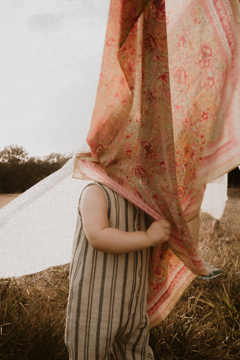 jouer dans les draps qui sechent lors de votre seance photo famille avec une photographe lifestyle des alpes maritimes