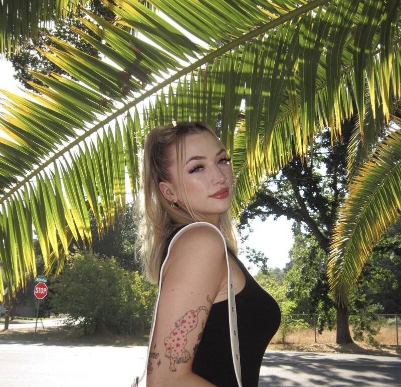 A women smiling at the camera in front of a palm tree