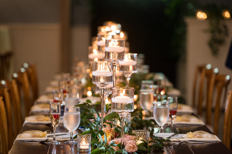 Elegant dining table set for a candlelit wedding reception at the Hotel LBI in Ship Bottom NJ, featuring tall candle holders and floral decorations, creating a warm and inviting ambiance perfect for a Jersey Shore wedding.