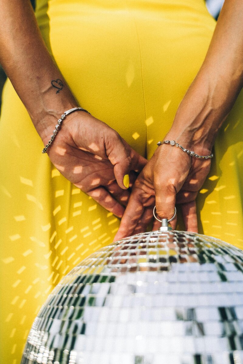 Lady in yellow holding a disco ball behind her back