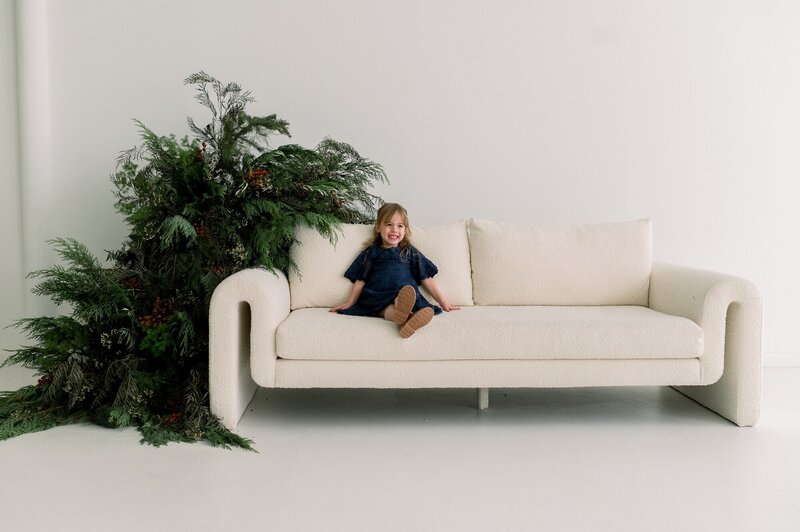 smiling girl on white couch with christmas florals.