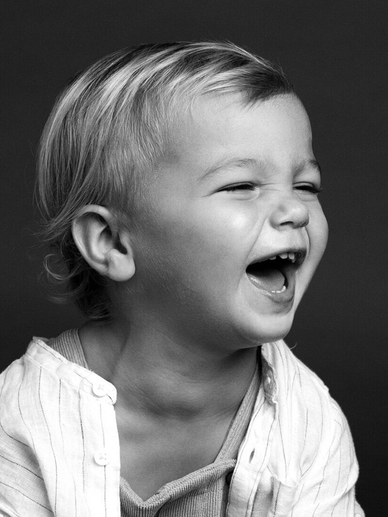 A black and white photo of a joyful toddler laughing, capturing a moment of pure happiness.
