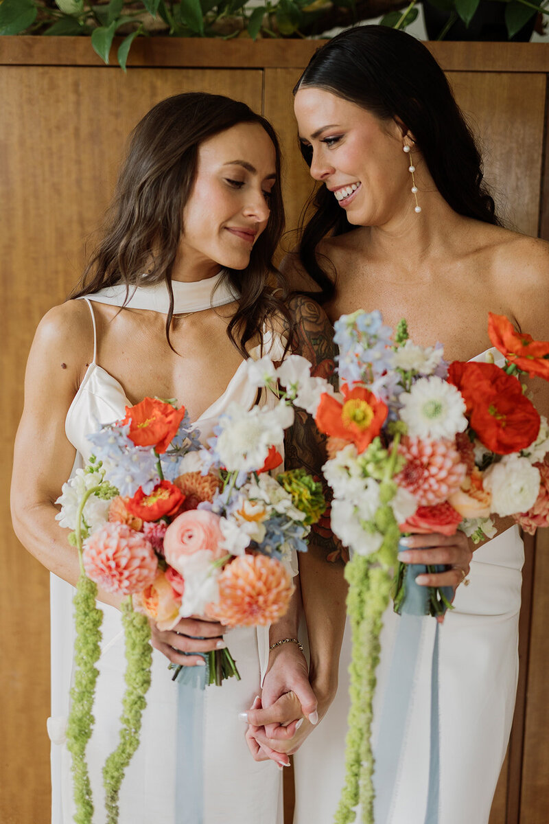 LGBTQ brides holding colorful bouquets at wedding planned by Bianca Nichole and Co