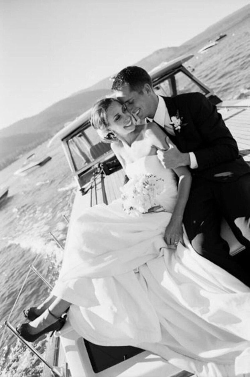 Black and white film image of a bride and groom snuggling on the top of a boat at Chambers Landing in Lake Tahoe