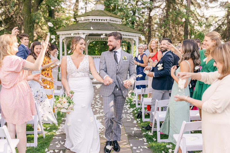 This heartwarming photograph captures the bride and groom walking down the aisle together, radiating happiness at The Norland Historic Estate, a charming and elegant wedding venue in Lethbridge Alberta.