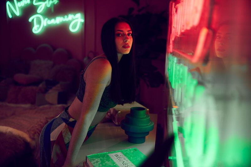 Dramatic lighting portrait of a teen model leaning into neon lights with a confident gaze – captured at an editorial-style mentorship shoot.