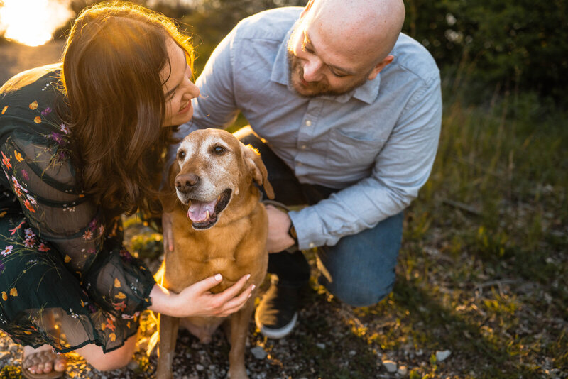 Couple kneel down to play with dog