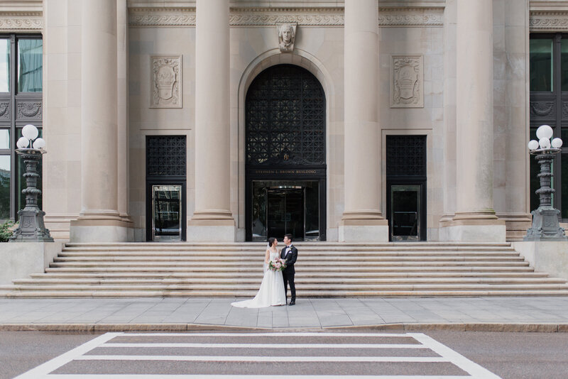 asian couple for a boston city wedding at the fairmont hotel. Bride kisses groom in black tux with stunning florals.