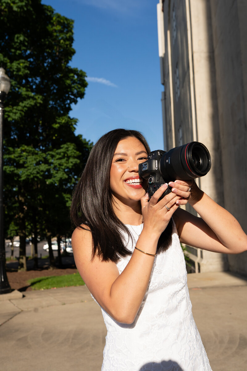 Woman sits on staircase looking down at camera preview screen with smile