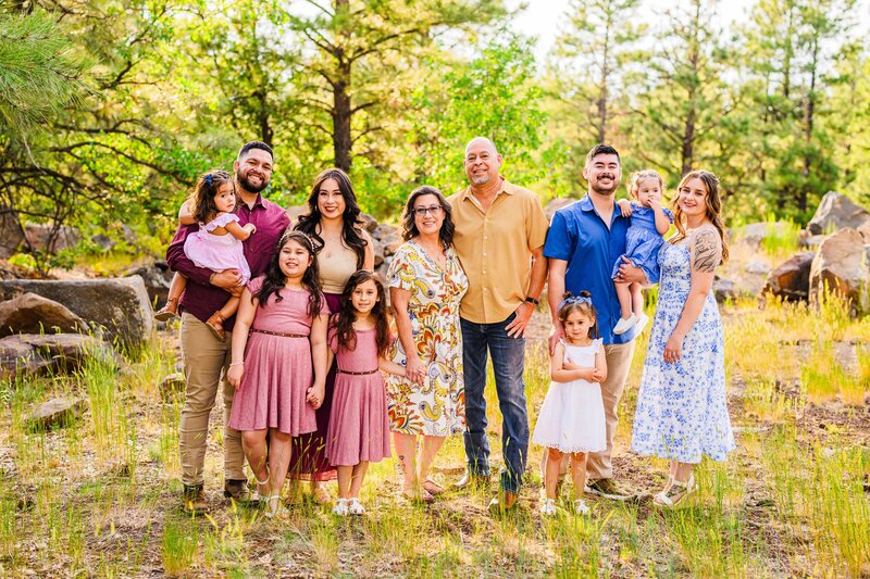 Large family in Flagstaff Arizona standing together smiling and looking at the camera with green woods background