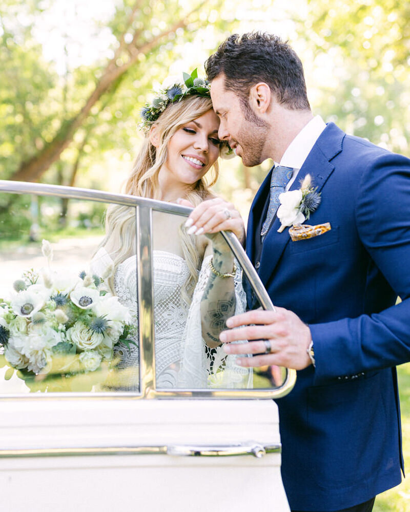 This elegant photograph captures the bride and groom holding each other outside the River Café on Prince's Island in Calgary. As they prepare to enter the luxurious white Rolls Royce, the moment reflects the sophistication and joy of their special day.