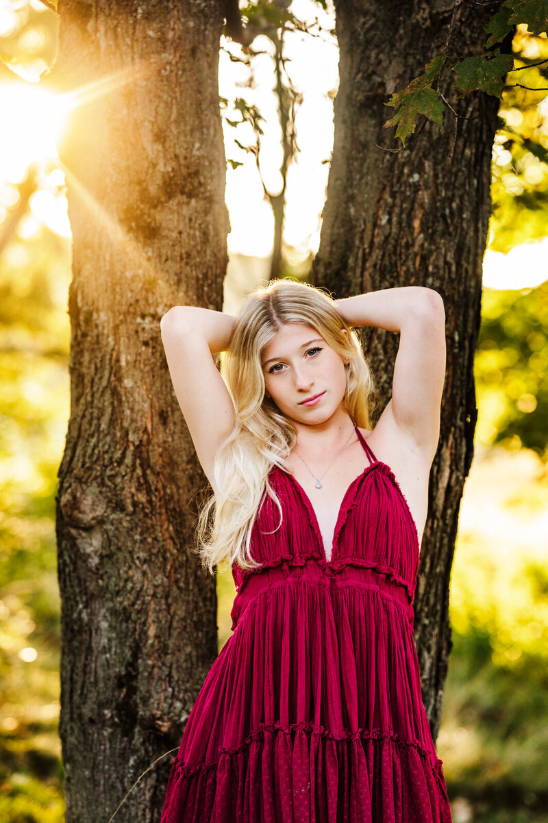 Girl standing in front of a tree holding her hair