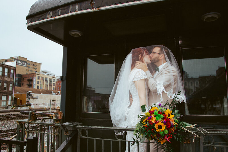 bride and groom kissing under veil on a train