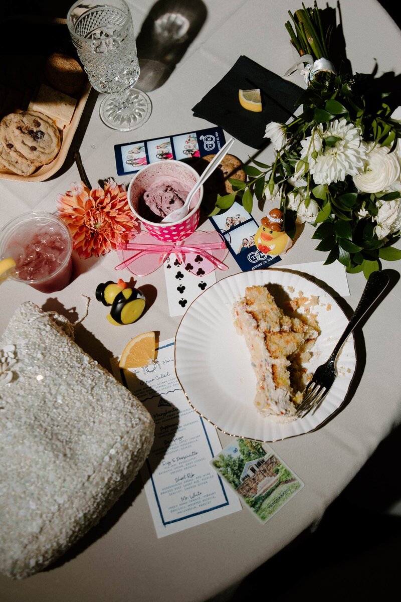 Half eaten desserts sitting on a wedding reception table with various pictures and gifts 