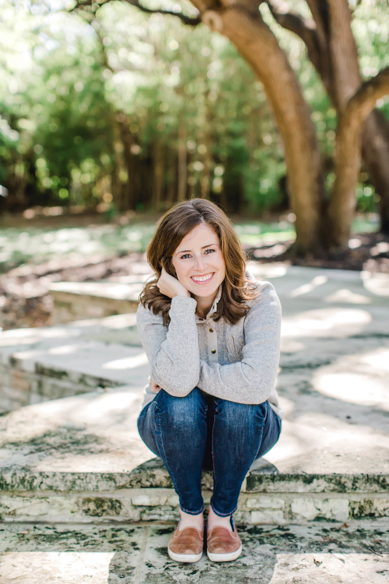 Photo of Amber Anderson sitting on step outside in grey sweater and jeans