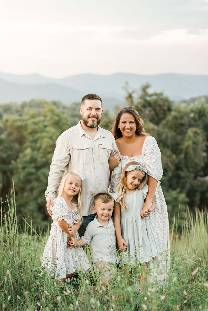 Ashley VanMeter stands with her husband and children, sharing a joyful family moment that reflects her passion for capturing love and connection through photography.