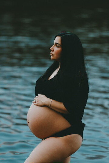 Black and white portrait of a pregnant mother holding her toddler, highlighting her bare baby bump and intimate connection – Fort Collins maternity and motherhood photography