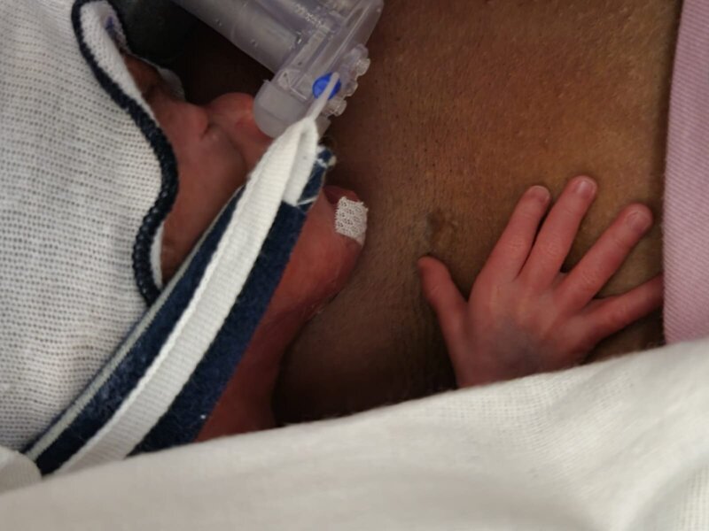 Black career coach for woring women holding NICU baby to chest