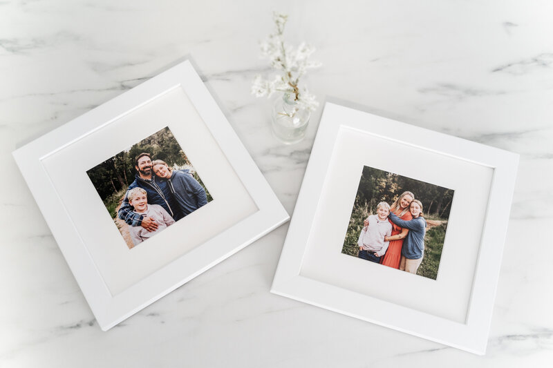Two framed family photos placed on a marble surface, each featuring a smiling family of three.