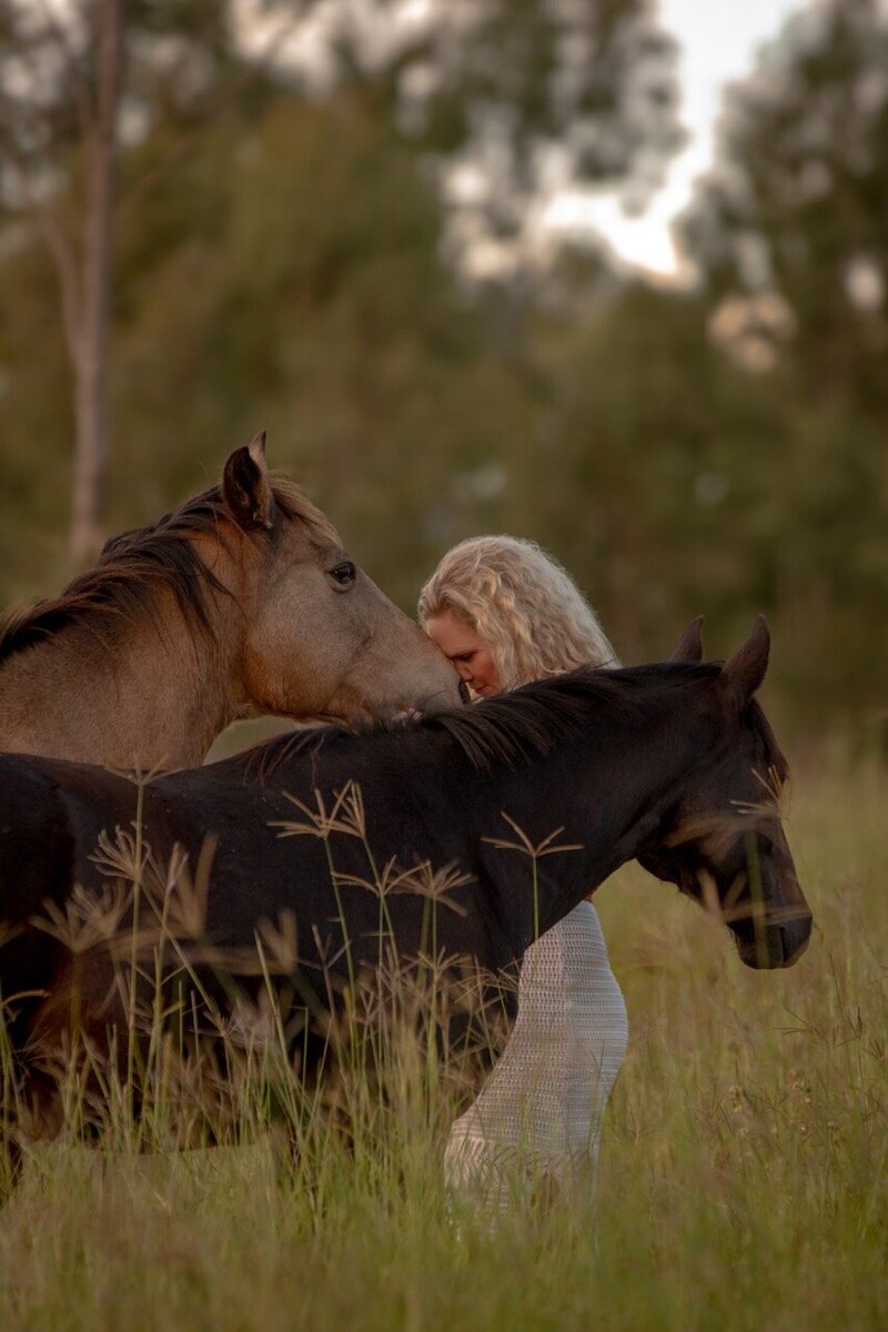 Woman touching her forehead to horse, being in the present moment during a horse retreat in Australia. 