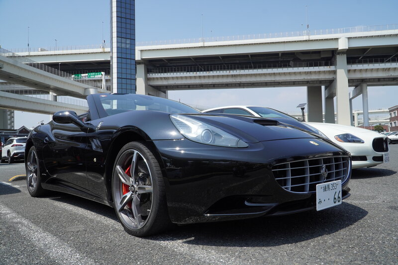 A black Ferrari California convertible parked under Tokyo’s elevated expressways, showcasing its iconic design and luxury detailing in the Tokyo Luxe Drive fleet.