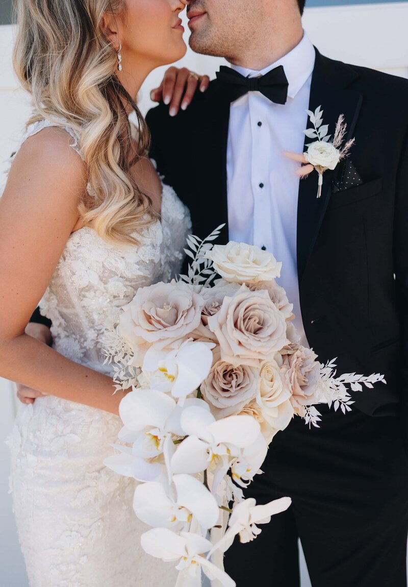 Couple embracing with orchid and rose filled bouquet - Mikayla & Mario | Harmony Meadows Luxury Wedding Lake Chelan Washington