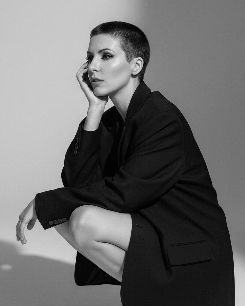 Artistic black and white portrait of Jasmina Kimova in short hair and black blazer, embodying sharp brand identity and reinvention