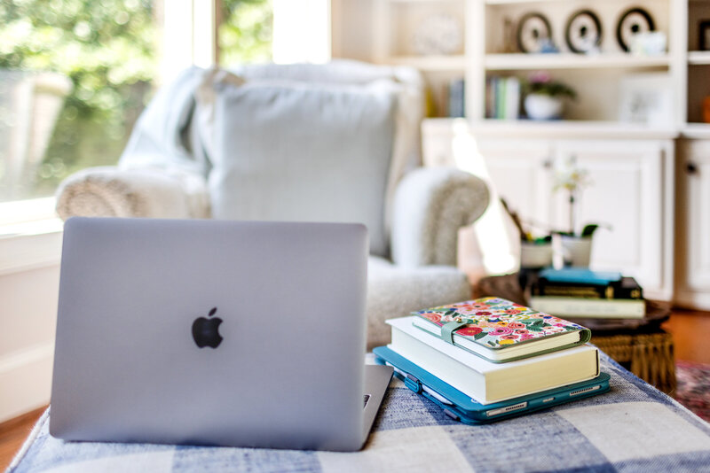 Laptop and therapy books sitting on an ottoman in a living room