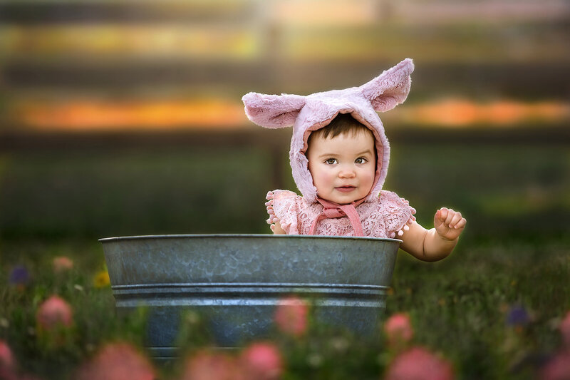 Sweet baby girl sitting inside a metal tub wearing a pig bonnet photographer by family photographer in Houston Danielle Dott.