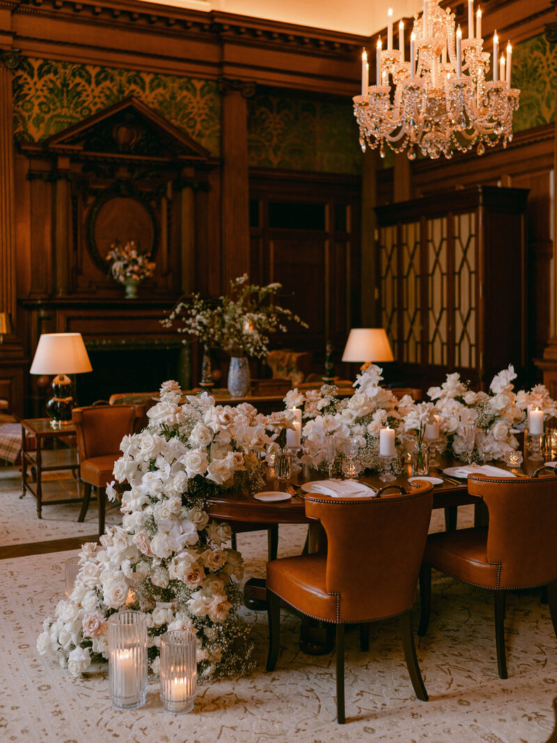 Elegant private event setup at Raffles London featuring a beautifully decorated table with cascading white floral arrangements and candles in a luxurious room.
