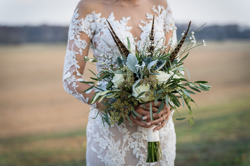 Bride with beautiful lace dress holding bouquet of flowers in a grassy field in San Antonio, Tx