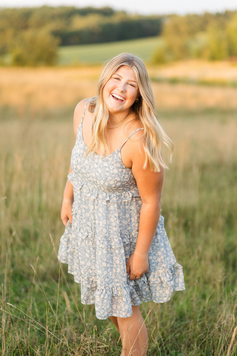 Girl smiling, posing outside in a field.