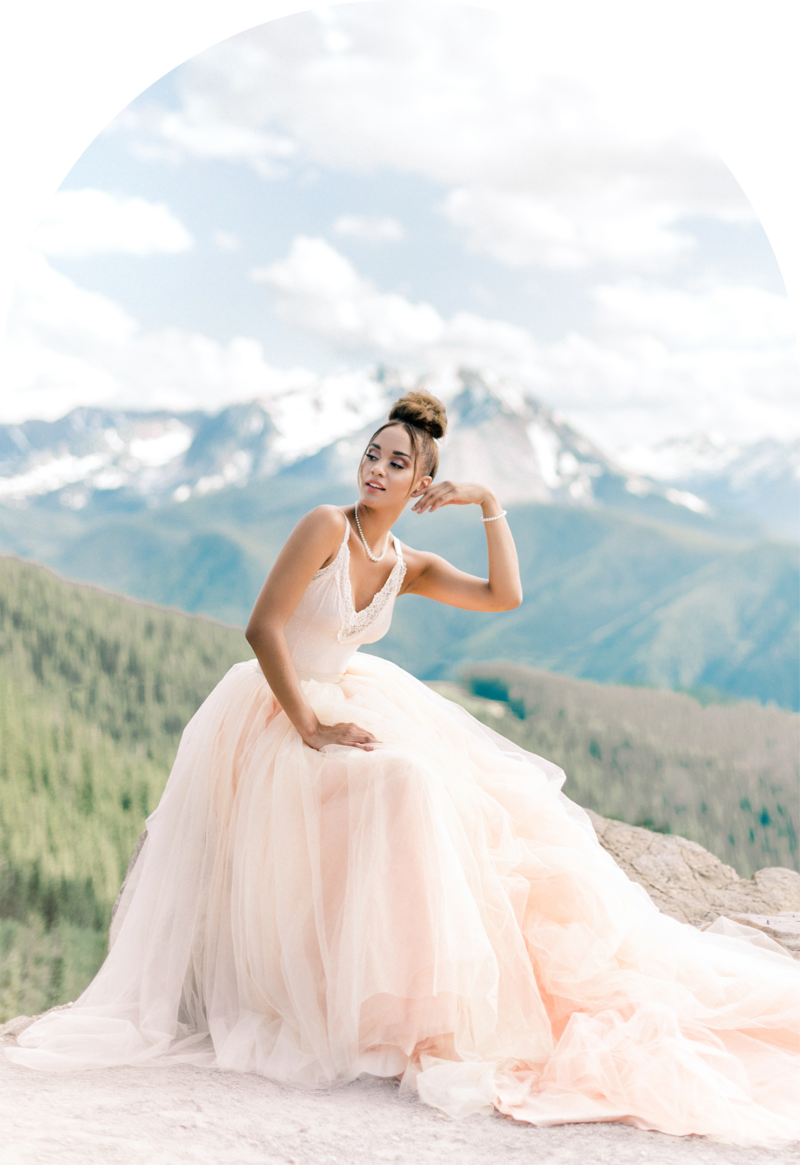 Bride in a fluffy pink dress on top of a mountain in Colorado.