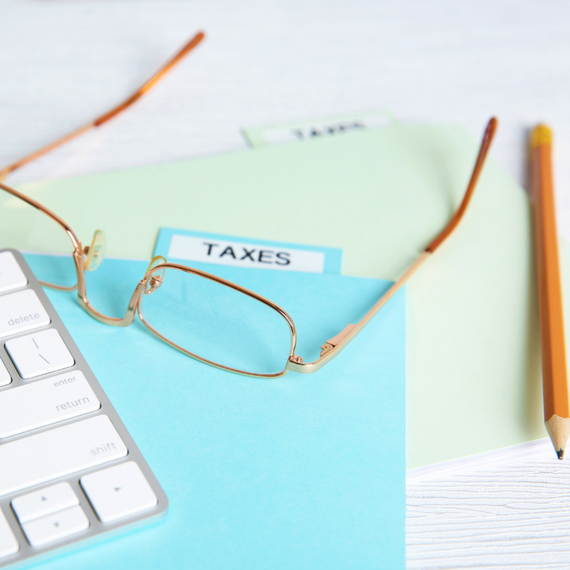 Taxation documents, glasses & a pencil next to a keyboard