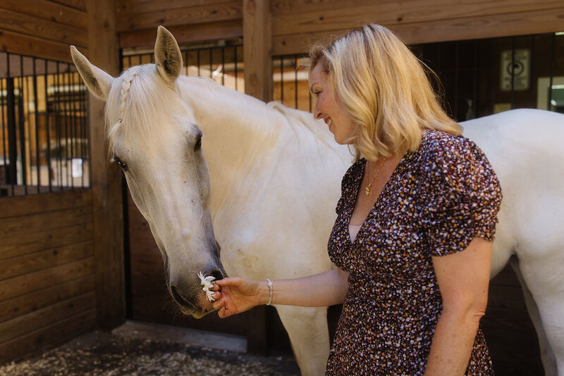 Leiko gently connecting with her horse inside a barn during an equine-guided session designed for horse owners seeking deeper understanding