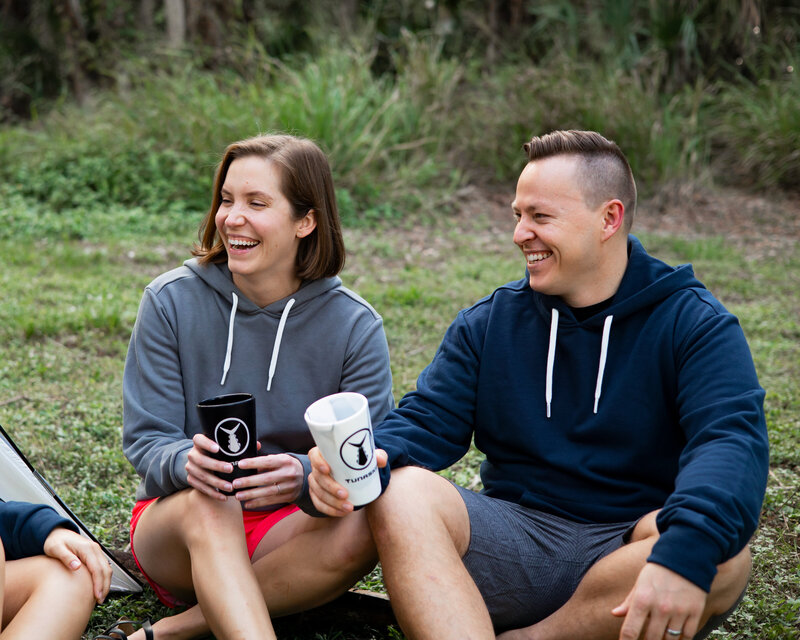 Two models sit near tent with dog for lifestyle activewear photoshot